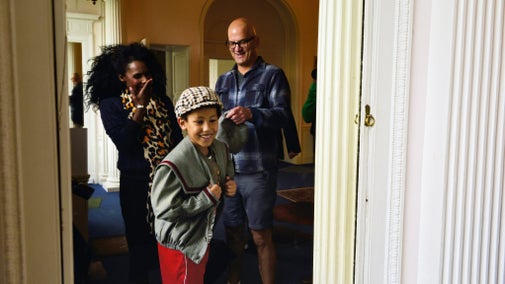 A boy dressing up laughing with a woman and man laughing too